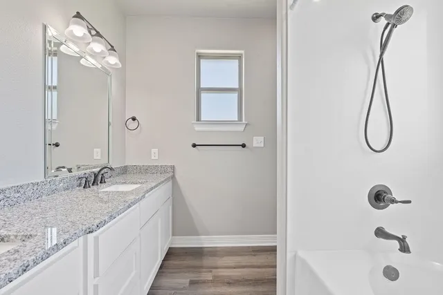 a bathroom with a granite countertop sink a mirror and shower