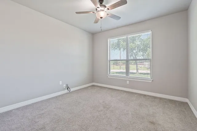 an empty room with a window and ceiling fan