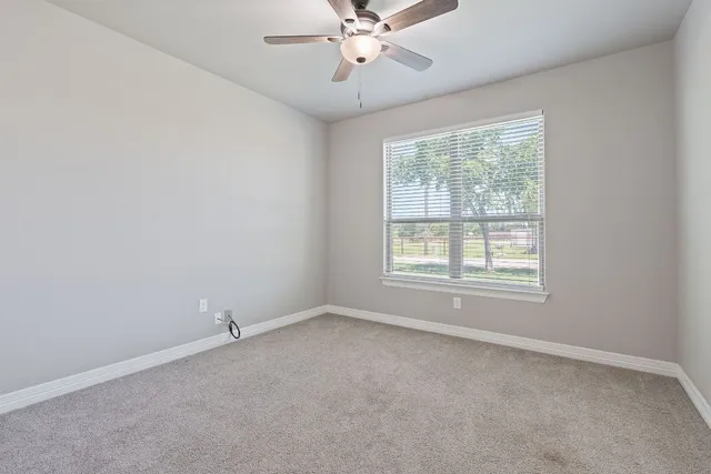 an empty room with a window and a fan
