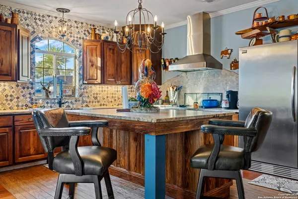 a kitchen with stainless steel appliances granite countertop a sink dishwasher and a flat screen tv