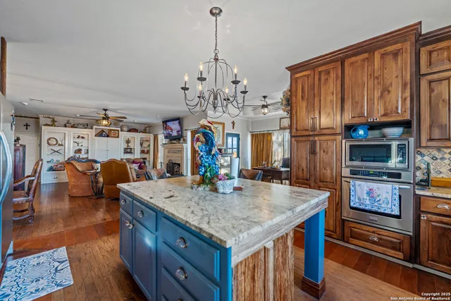 a kitchen with stainless steel appliances granite countertop a sink a stove and a wooden cabinets