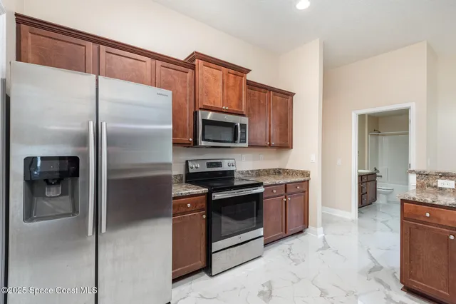 a kitchen with stainless steel appliances granite countertop a refrigerator a stove and a sink