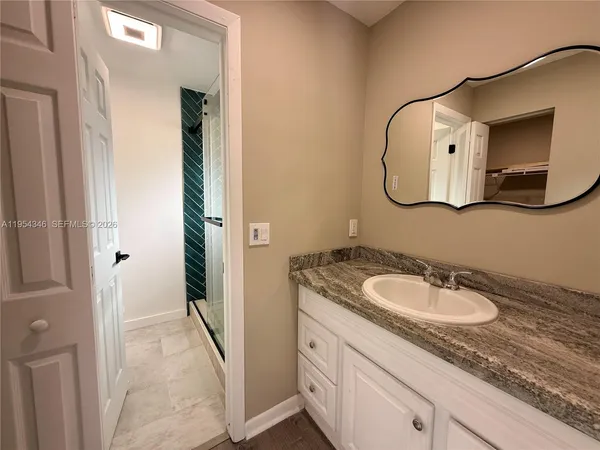 a bathroom with a granite countertop sink and a mirror