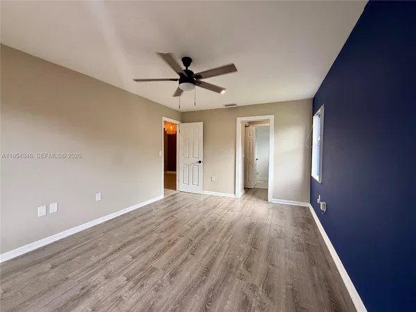 a view of empty room with wooden floor and fan
