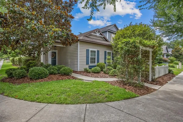 a view of a house with a small yard plants and large tree