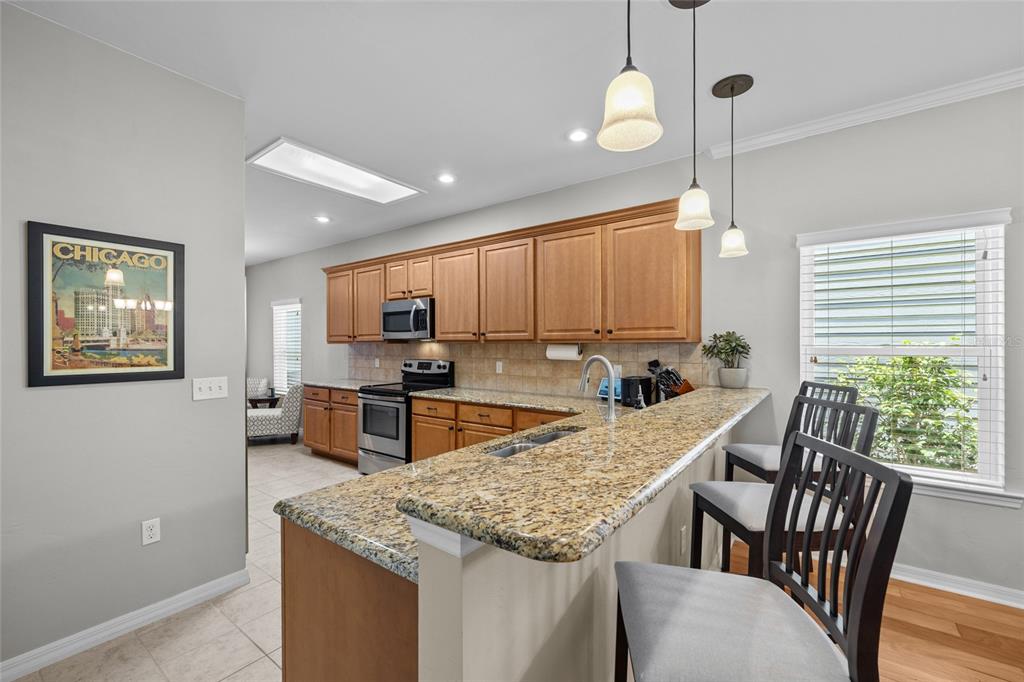8251 Southwest 78th Lane Gainesville, FL 32608 - Photo 10 of 29 a kitchen with stainless steel appliances granite countertop a stove a sink a microwave oven with a dining table and chairs