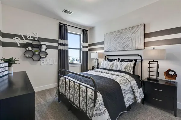 a bedroom with a bed and a lamp on dresser