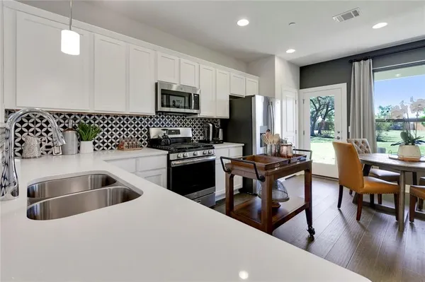 a kitchen with stainless steel appliances a stove a sink a microwave a dining table and chairs