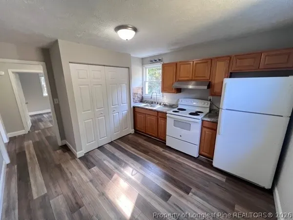 a kitchen with stainless steel appliances a refrigerator and wooden floors