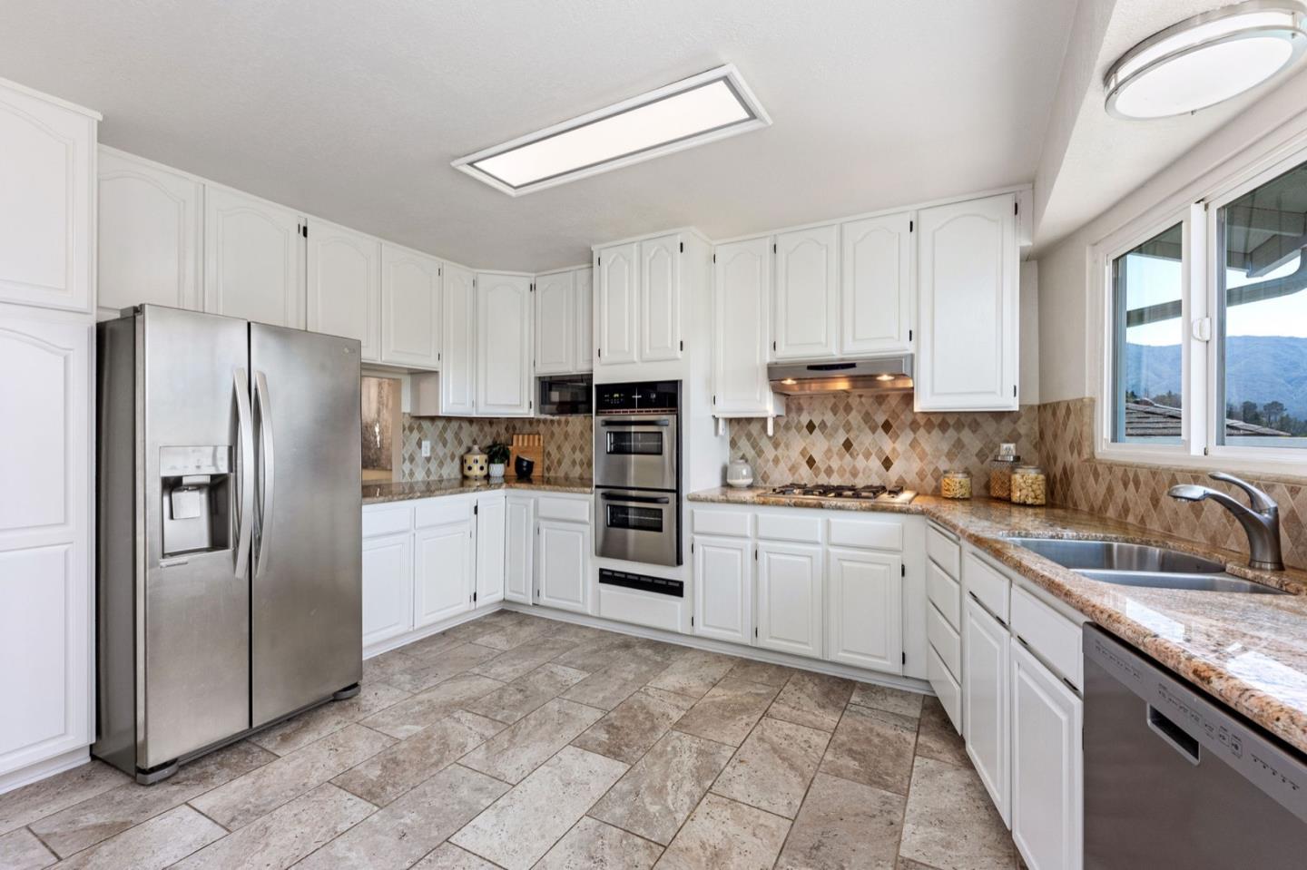 1063 Glacier Avenue Pacifica, CA 94044 - Photo 17 of 63 a kitchen with granite countertop a refrigerator sink and cabinets