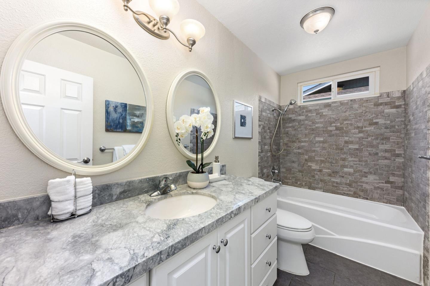 1063 Glacier Avenue Pacifica, CA 94044 - Photo 27 of 63 a bathroom with a granite countertop toilet a sink and a mirror