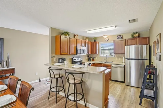 a kitchen with stainless steel appliances a dining table chairs refrigerator and sink