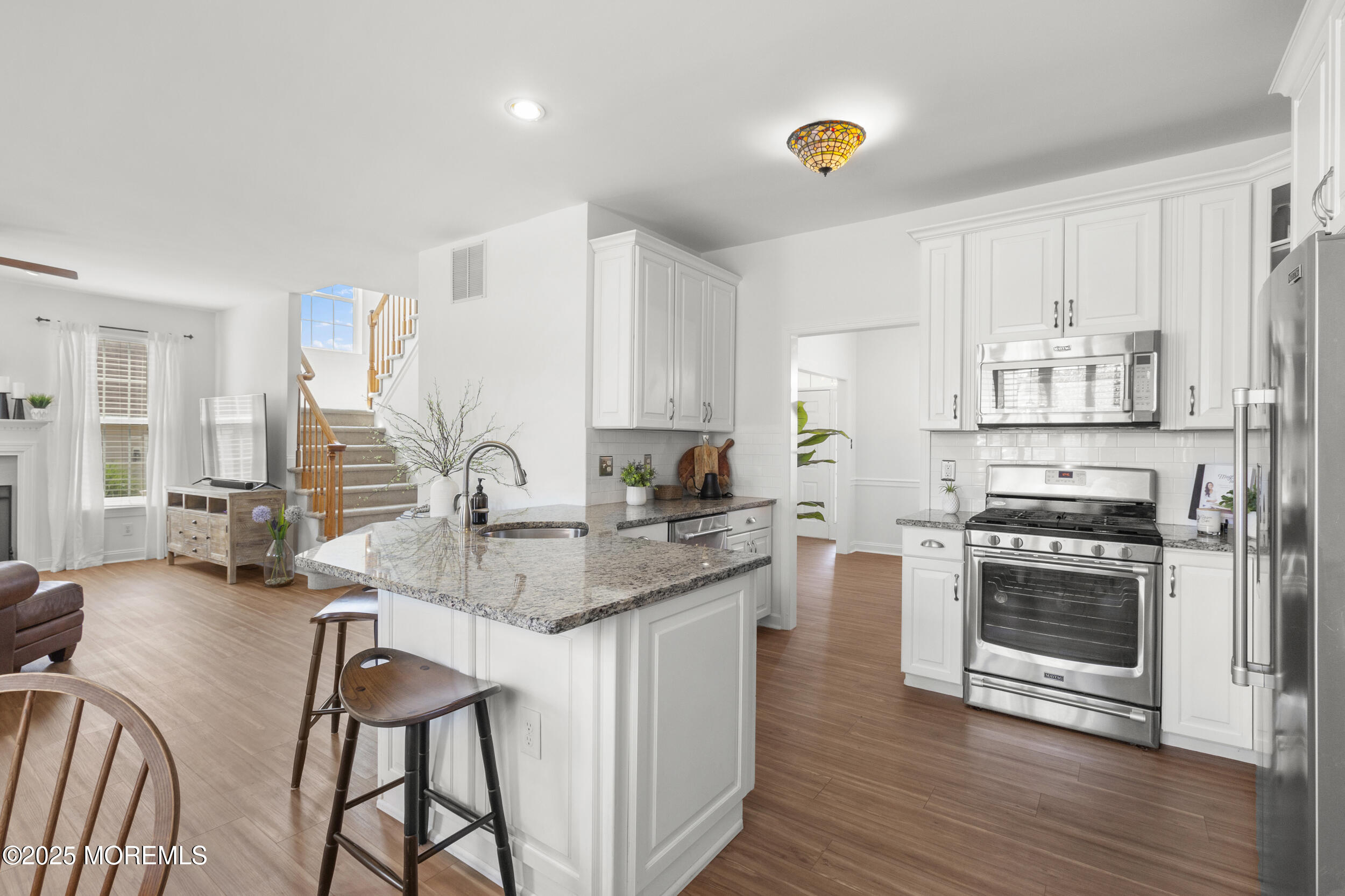 27 Danella Way Howell, NJ 07731 - Photo 5 of 25 a kitchen with stainless steel appliances granite countertop a stove a sink dishwasher a microwave oven with a dining table and chairs
