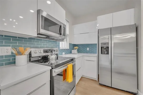 a kitchen with stainless steel appliances granite countertop a refrigerator a stove and a sink with wooden floor