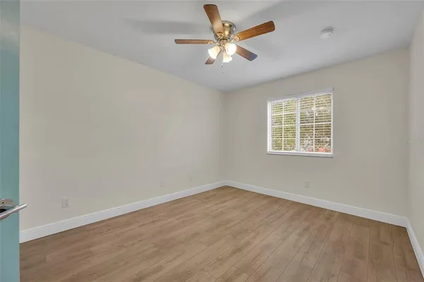 an empty room with a window and a fan