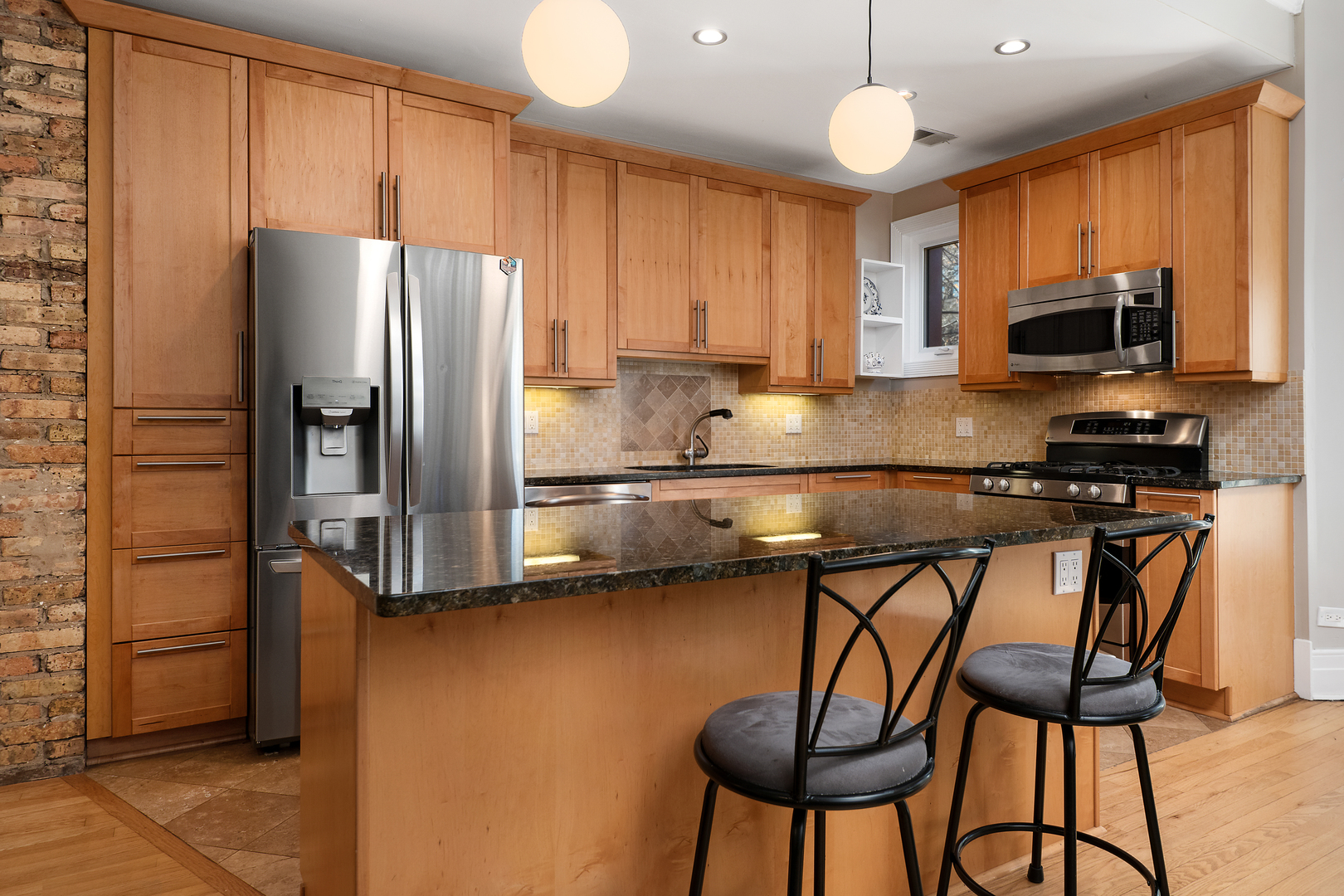 4061 North Sheridan Road, Unit 1 Chicago, IL 60613 - Photo 7 of 26 a kitchen with stainless steel appliances granite countertop a refrigerator a stove a sink dishwasher and a microwave with wooden floor