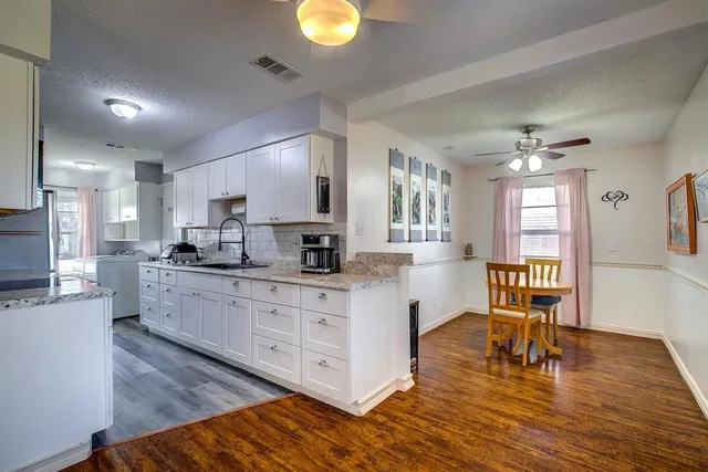 a kitchen with stainless steel appliances granite countertop a stove top oven a sink dishwasher a dining table and chairs with wooden floor