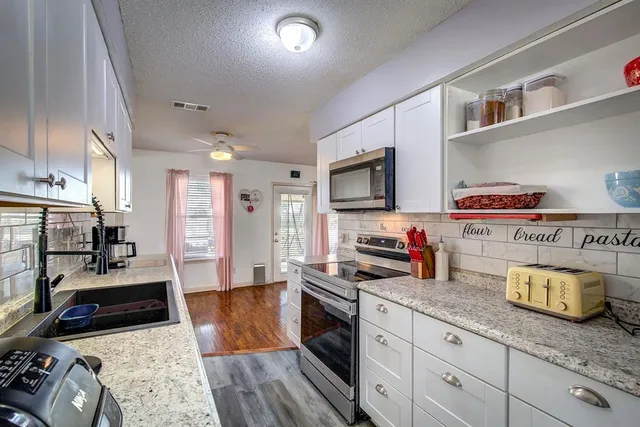 a kitchen with granite countertop a stove and cabinets