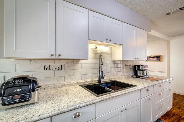 a kitchen with granite countertop a sink a stove and cabinets