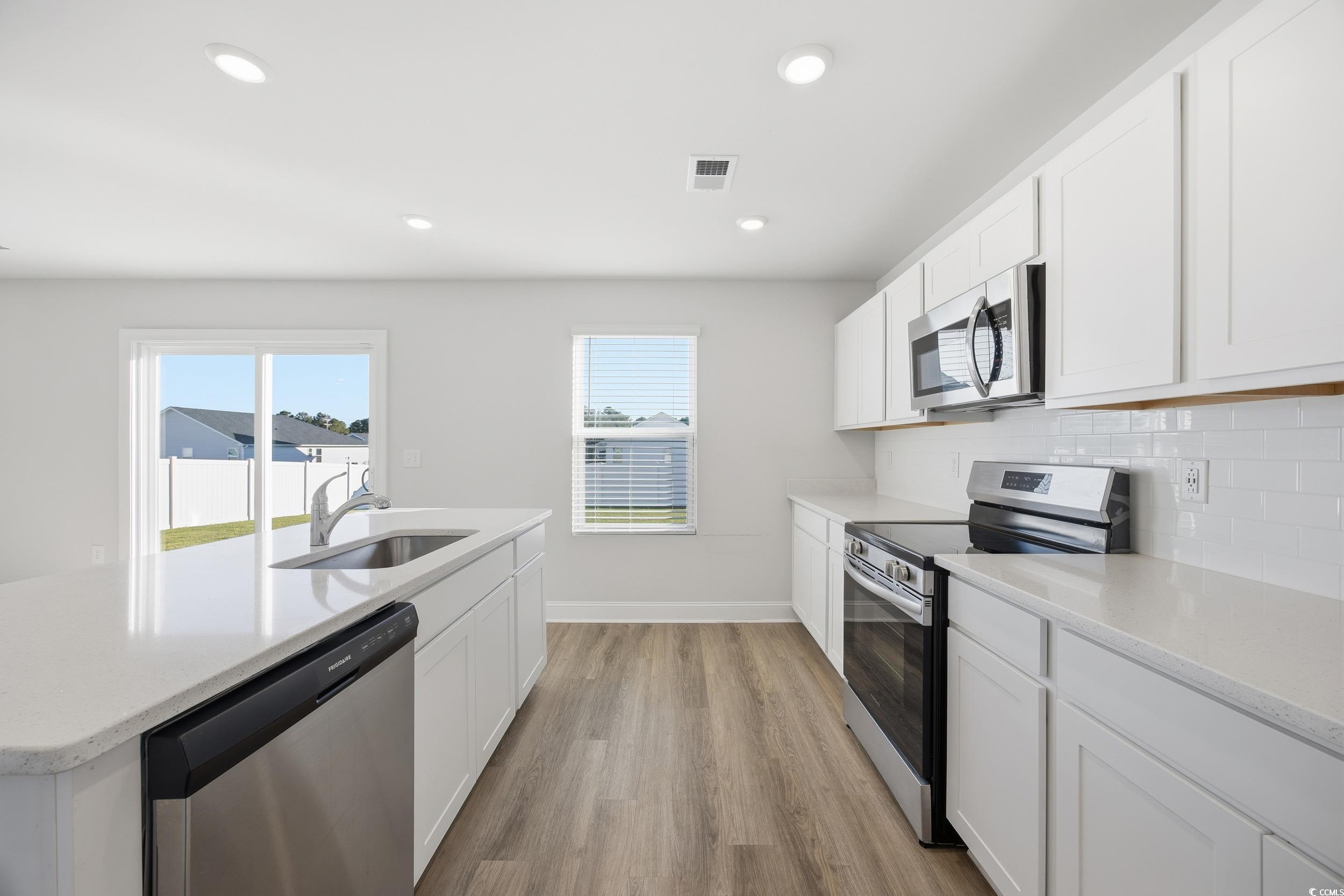 1052 Kinness Drive Conway, SC 29527 - Photo 11 of 38 Kitchen with appliances with stainless steel finishes, white cabinets, light wood-type flooring, a kitchen island with sink, and light stone countertops