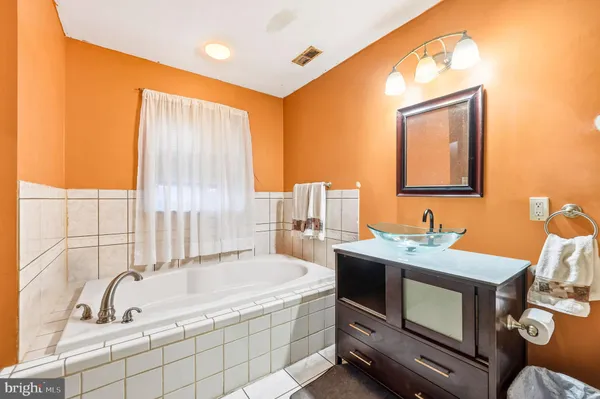 a spacious bathroom with a tub sink and mirror