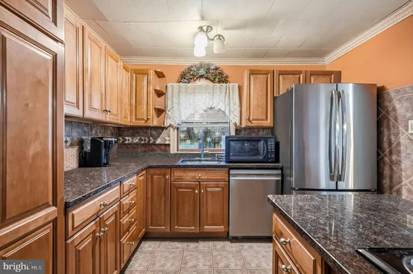 a kitchen with stainless steel appliances granite countertop a refrigerator a oven and white cabinets
