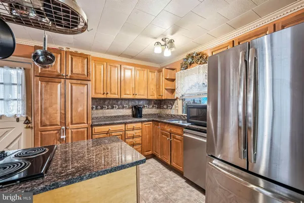 a kitchen with stainless steel appliances granite countertop a refrigerator a sink dishwasher a stove and white countertops with wooden floor