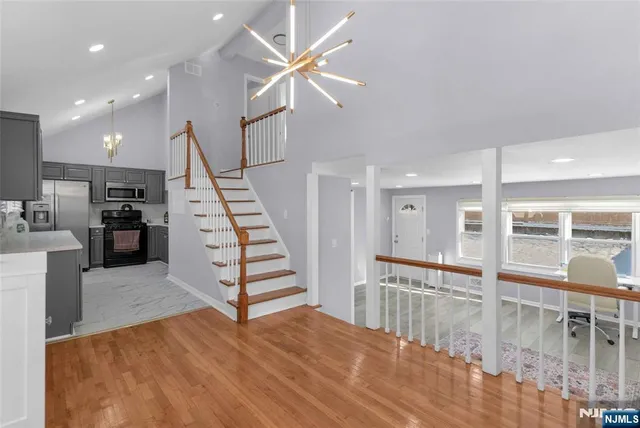 a view of a living room with wooden floor and white walls