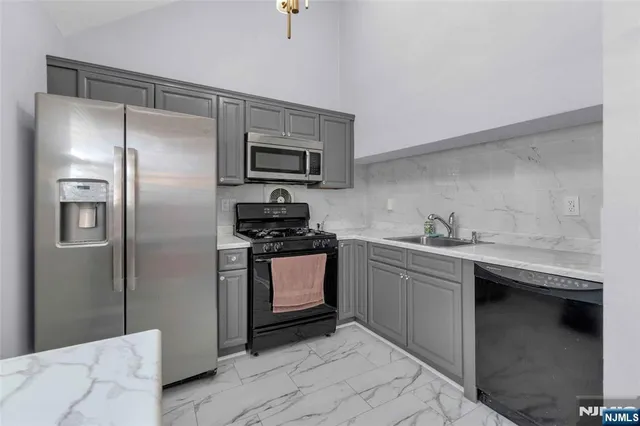a kitchen with stainless steel appliances granite countertop a sink and a refrigerator