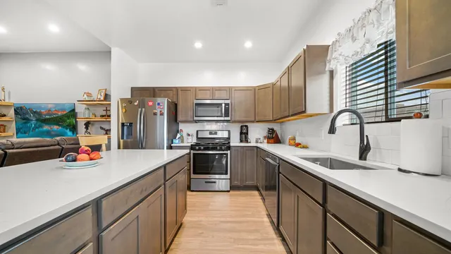 a kitchen with stainless steel appliances granite countertop a sink dishwasher a stove refrigerator and cabinets with wooden floor