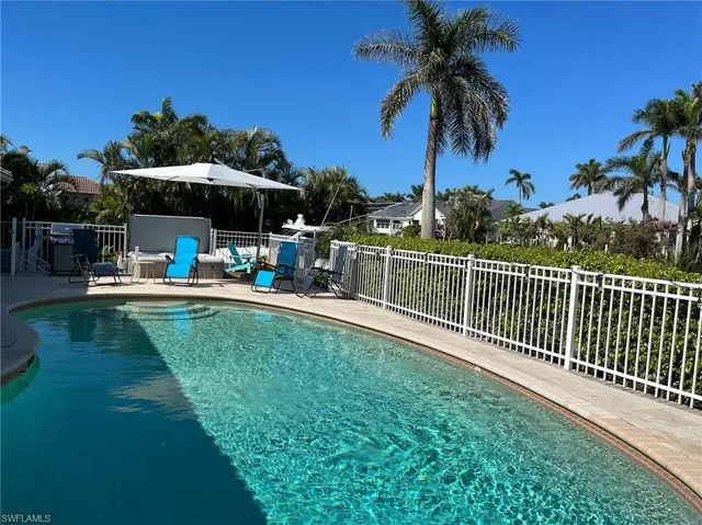 a view of a swimming pool with a table and chairs under an umbrella