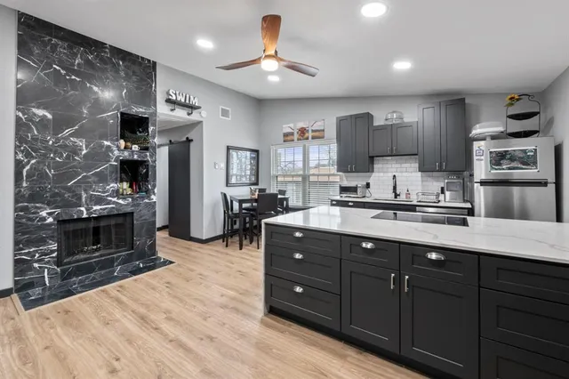 a kitchen with stainless steel appliances kitchen island granite countertop a refrigerator oven a sink dishwasher and white cabinets with wooden floor