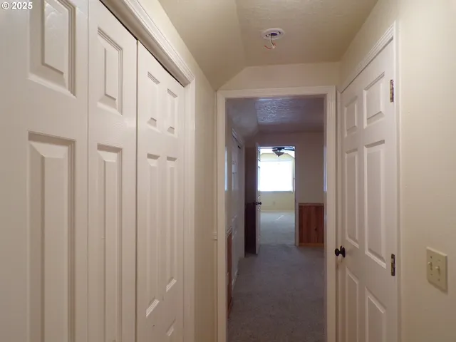 a view of a hallway with wooden floor and closet