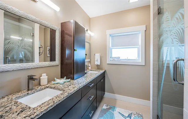 a bathroom with a granite countertop double vanity sink and mirror