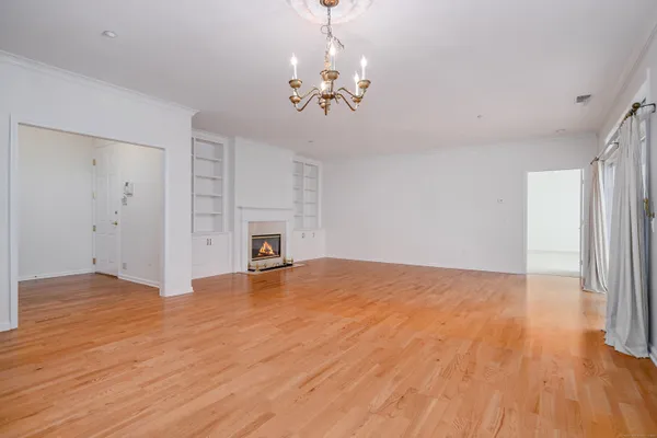 a view of empty room with wooden floor and fireplace