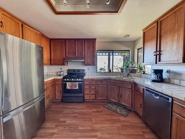 a kitchen with stainless steel appliances granite countertop a refrigerator stove and wooden cabinets