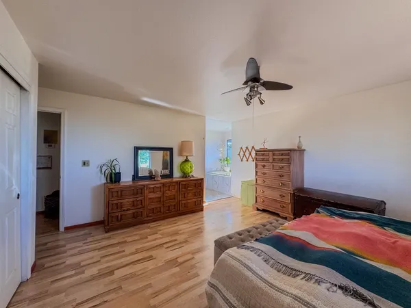 a bedroom with a bed a dresser and wooden floor