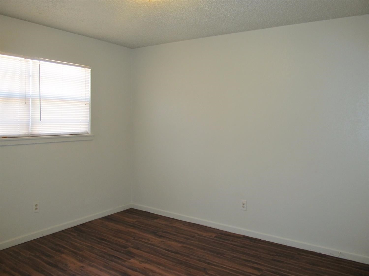 4516 35th Street, Unit B Lubbock, TX 79414 - Photo 6 of 7 an empty room with wooden floor and windows