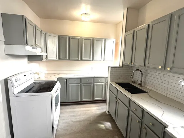 a kitchen that has a sink a stove and cabinets