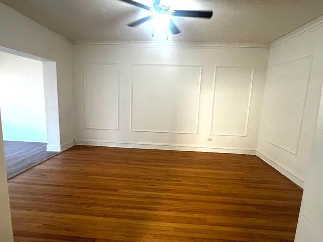 an empty room with wooden floor fan and windows