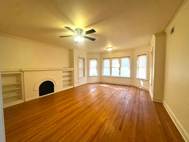 a view of an empty room with window and wooden floor