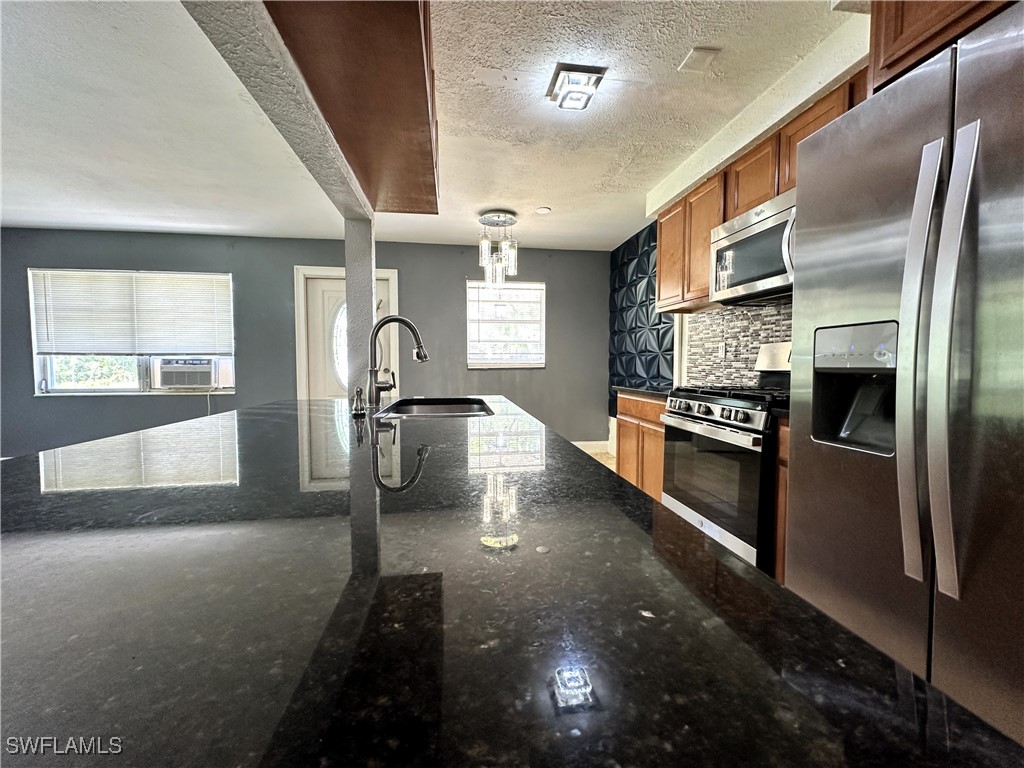 818 Sheldon Avenue Lehigh Acres, FL 33936 - Photo 16 of 43 a kitchen with stainless steel appliances granite countertop a refrigerator a stove and a sink with wooden floor