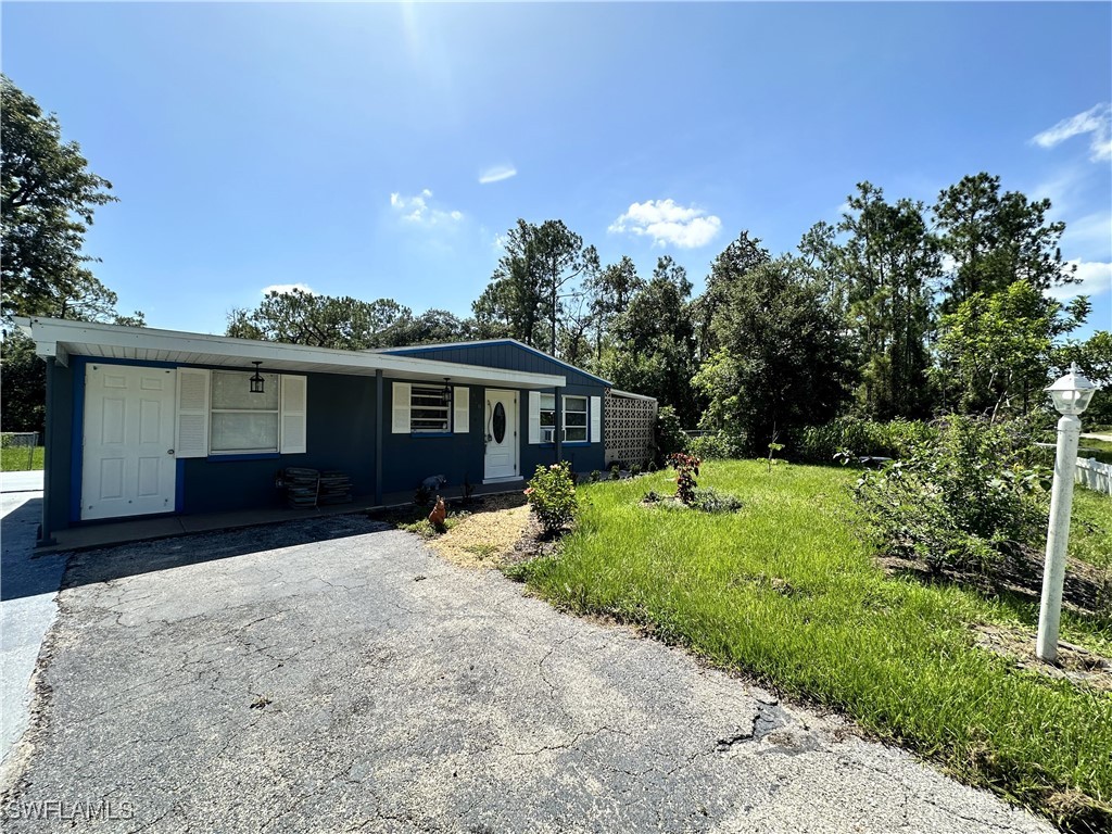 818 Sheldon Avenue Lehigh Acres, FL 33936 - Photo 4 of 43 a front view of a house with a yard and trees