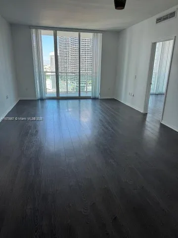 a view of an empty room with wooden floor and a window