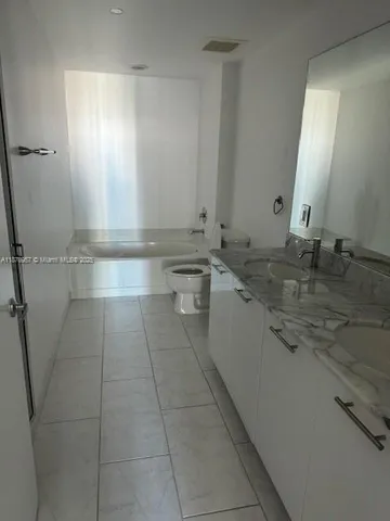 a bathroom with a granite countertop sink a mirror and a bathtub