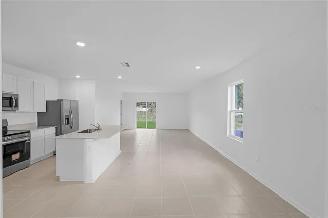 a large white kitchen with stainless steel appliances a large window