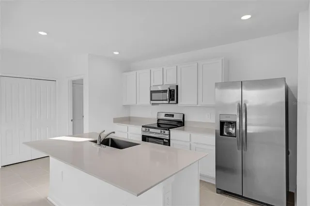 a kitchen with stainless steel appliances a refrigerator sink and white cabinets
