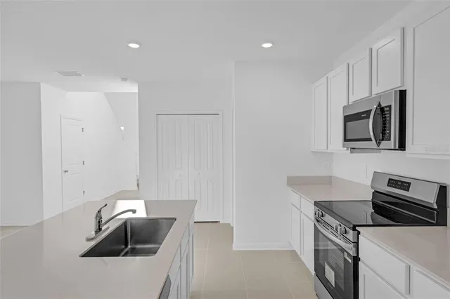 a kitchen with granite countertop a sink dishwasher stove and microwave with wooden floor