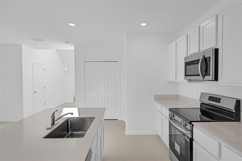 5428 Meadow Walk Drive Davenport, FL 33837 - Photo 10 of 24 a kitchen with granite countertop a sink dishwasher stove and microwave with wooden floor