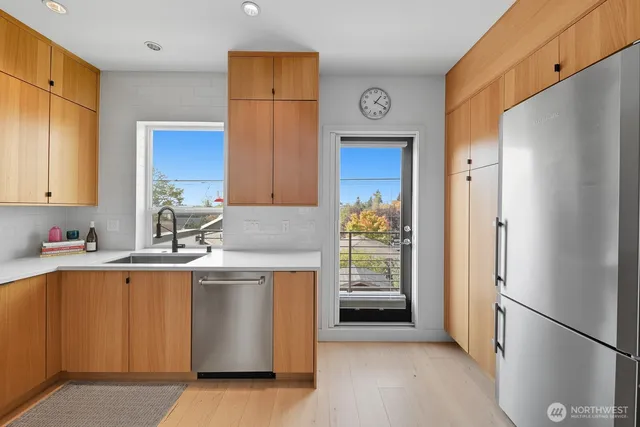 a kitchen with stainless steel appliances granite countertop a refrigerator a stove and a sink with wooden floor